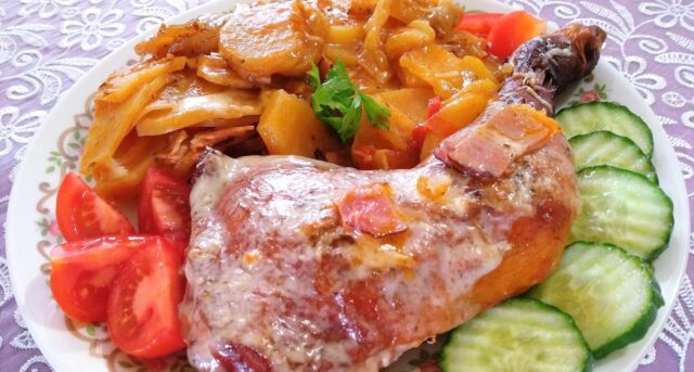 Pečené kuřecí stehno s bramborami a zeleninou na talíři.