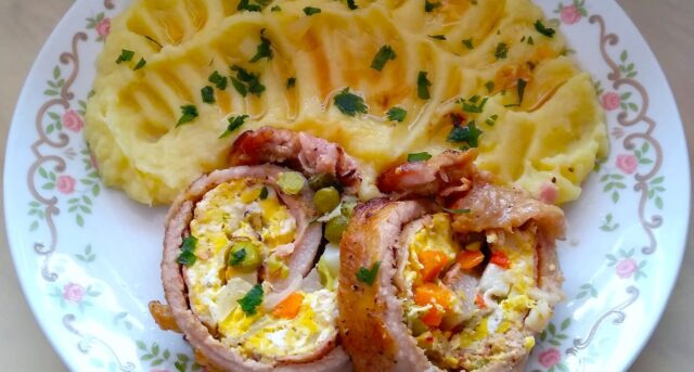 Plněná vepřová roláda s vejcem a zeleninou, podávaná s bramborovou kaší.