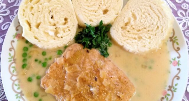 Vepřový plátek v jemné omáčce s hráškem, podávaný s houskovým knedlíkem.