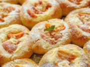 Vláčné kynuté koláče s vanilkovým pudinkem, meruňkami a rumovým máslem Plech plný zlatavých kulatých kynutých koláčů s pudinkem, zářivě oranžovými meruňkami a křupavou drobenkou, lesklé potřené okraje.