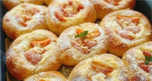 Vláčné kynuté koláče s vanilkovým pudinkem, meruňkami a rumovým máslem Plech plný zlatavých kulatých kynutých koláčů s pudinkem, zářivě oranžovými meruňkami a křupavou drobenkou, lesklé potřené okraje.