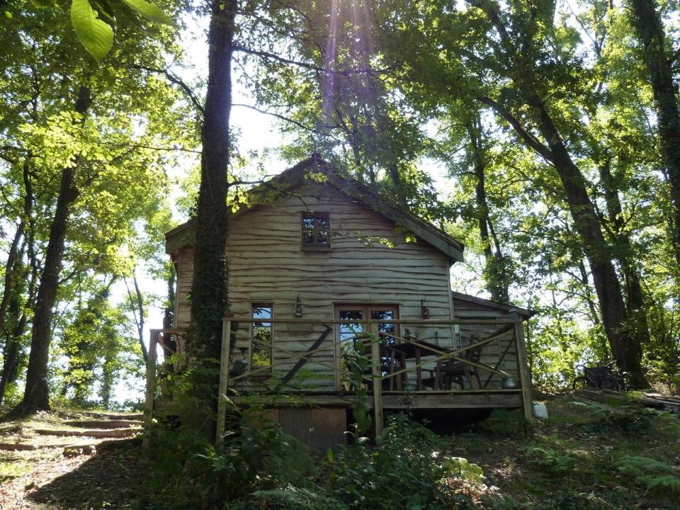 Rustikální chata obklopená břízami, jasany a duby
